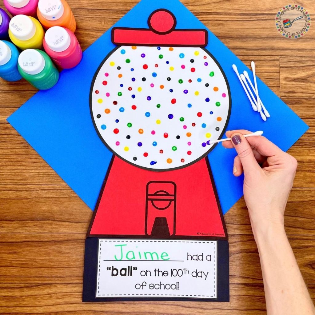 Student is making a 100th day of school gumball machine using painted Q-tips. They are using 10 different colors of paint and making 10 dots with each color to have 100 dots or gumballs altogether. 
