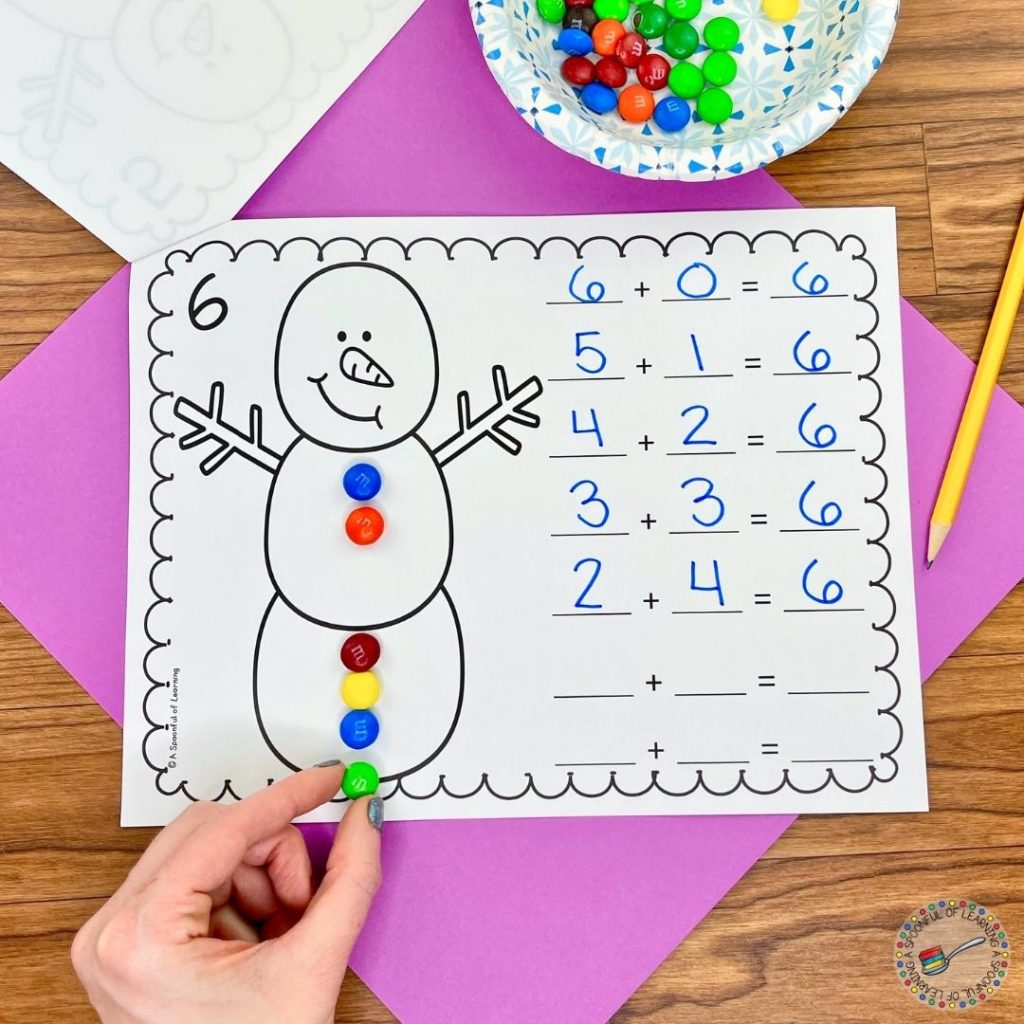 Student practicing decomposing numbers by sliding M&M's on the snowman's body to decompose the given numbers and creating all of the addition equations for the given sum.