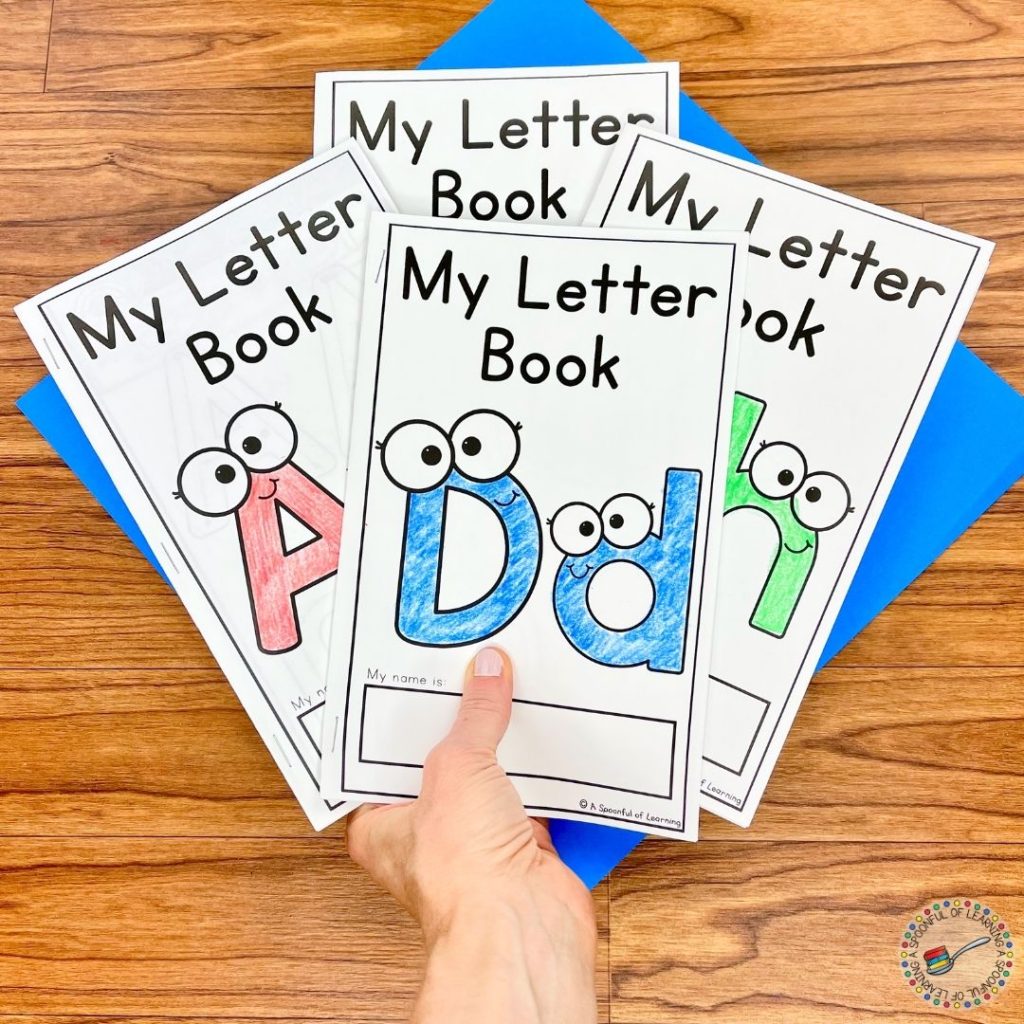 A hand is holding multiple completed alphabet books