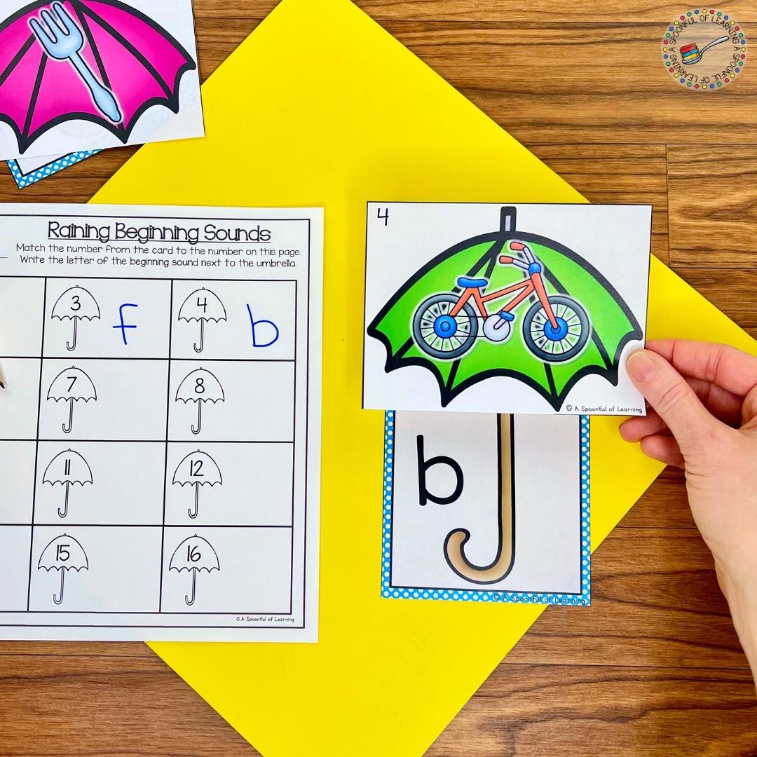 An example of a beginning sounds literacy activity where the students match the picture on the canopy of the umbrella to the correct beginning sound letter next to the handle of the umbrella to build an umbrella.