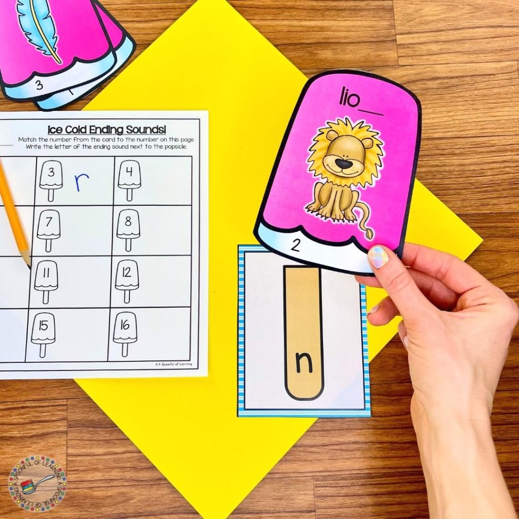 Adding the top of a popsicle with a picture of a lion to a popsicle stick with the correct ending sound.