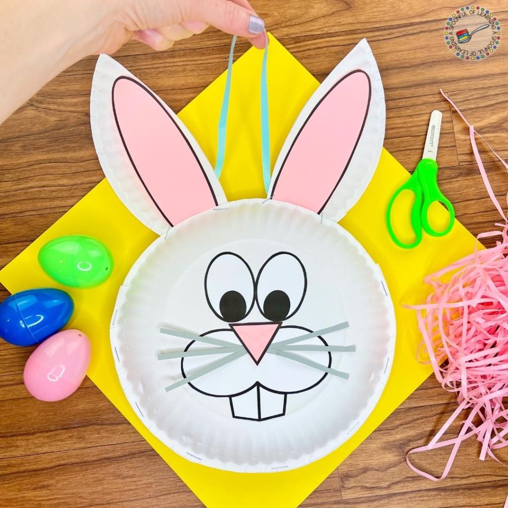 An Easter Bunny craft that is made with paper plates and turned into a basket that holds plastic Easter eggs.