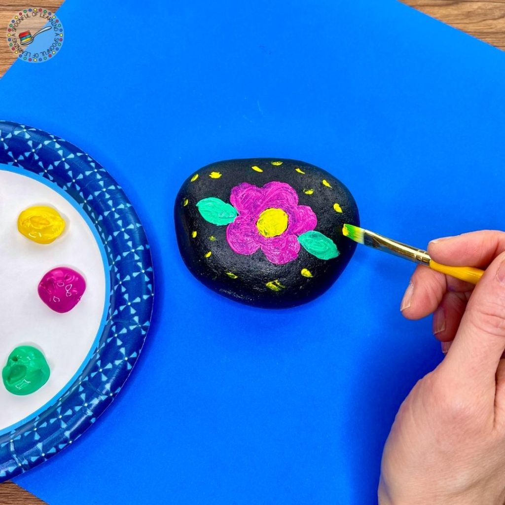 Painting a flower on a rock.