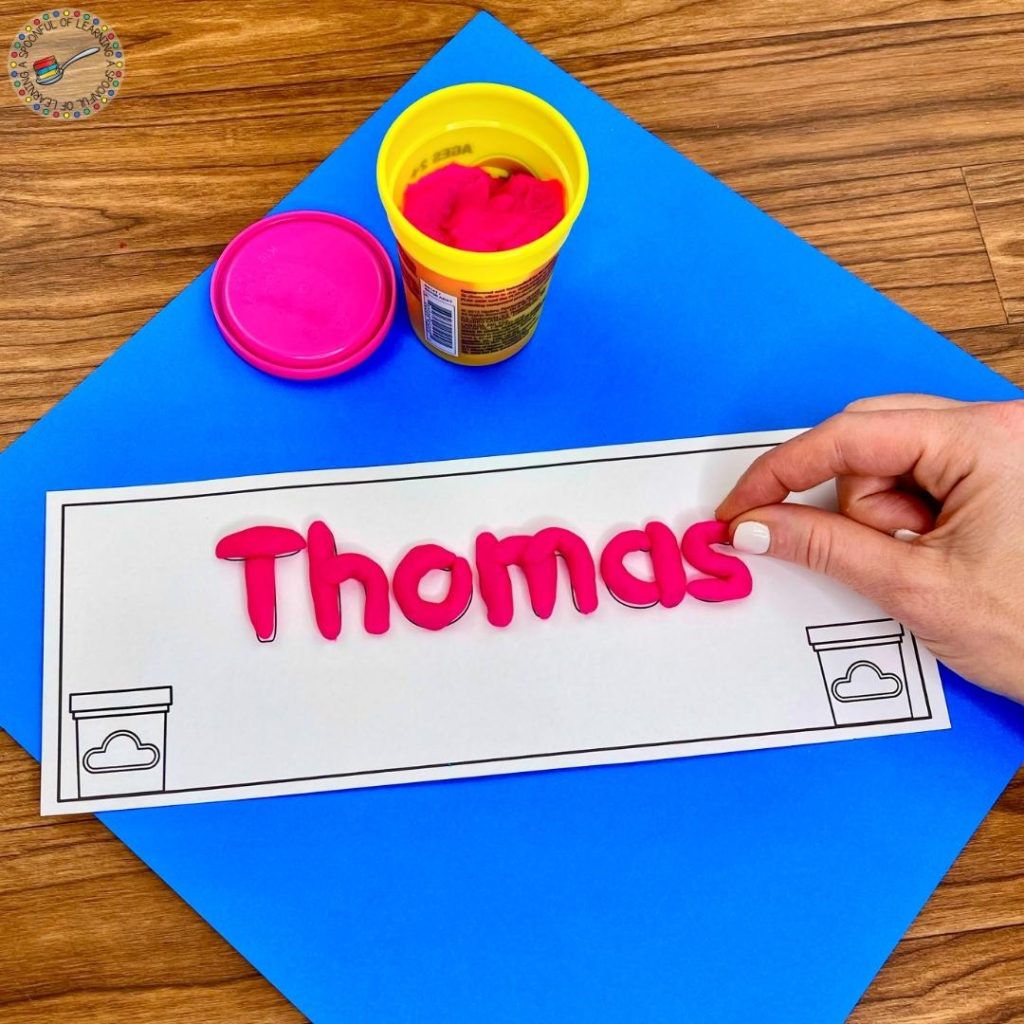 Forming the name "Thomas" with pink play dough