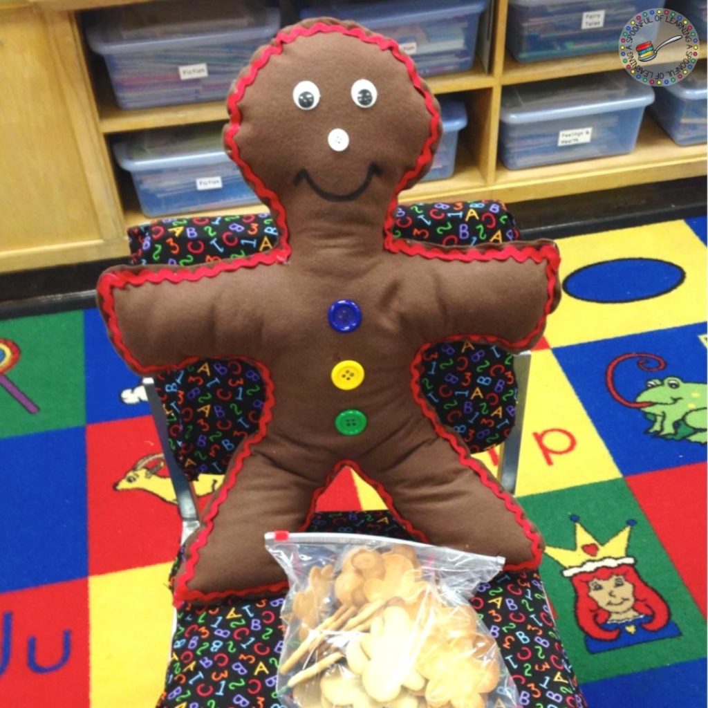 A plush gingerbread man sits on a classroom chair with a bag of cookies
