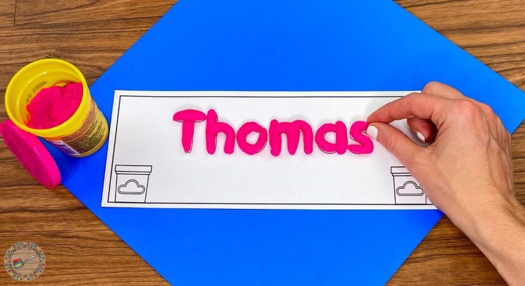 The name Thomas is being spelled with play dough