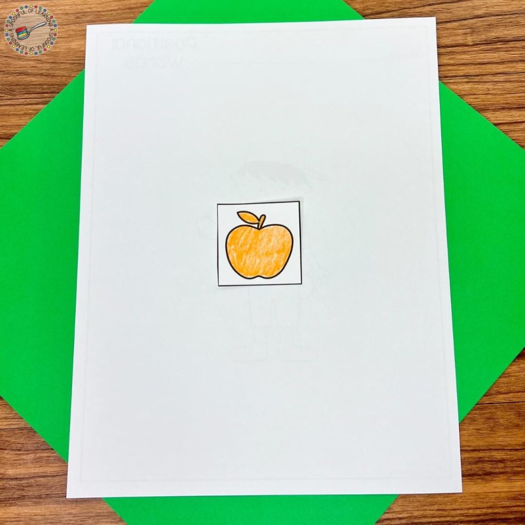 Pasting an apple on the back of a positional words worksheet