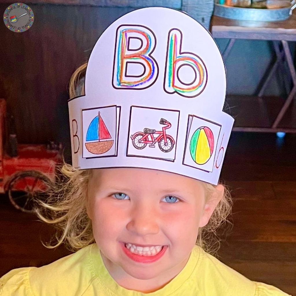 A smiling child wearing an alphabet hat for the letter B