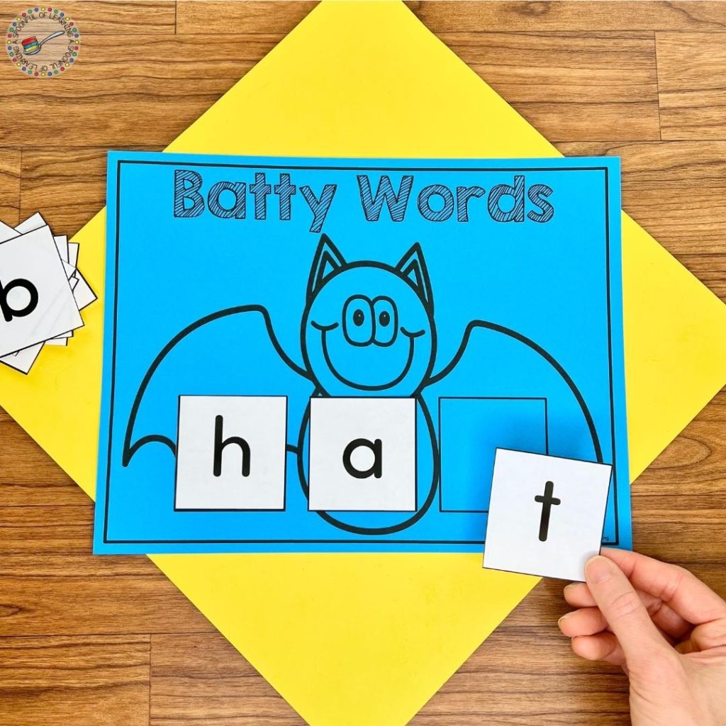 Spelling out the word hat on a bat word building mat
