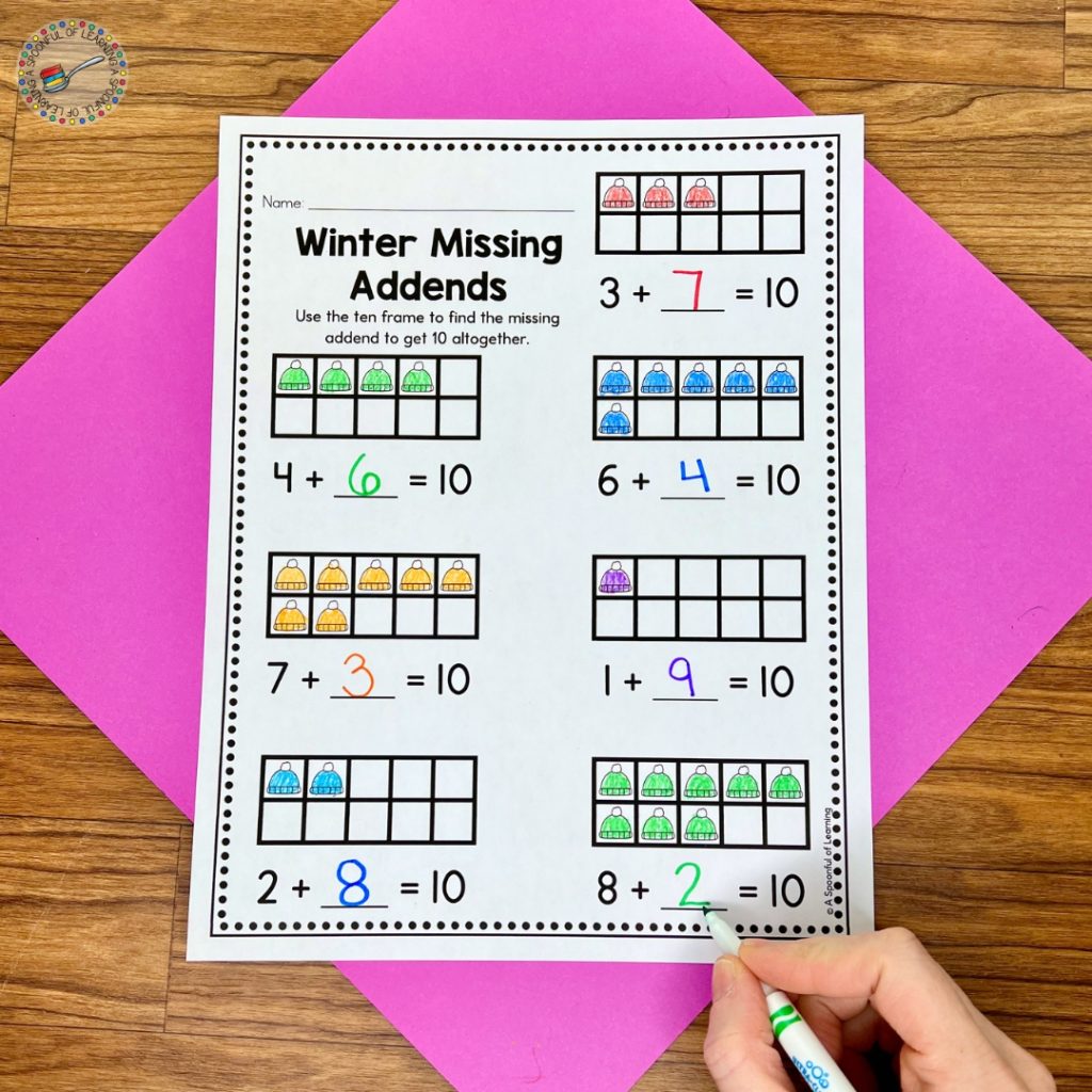 Completing a winter missing addends worksheet with marker