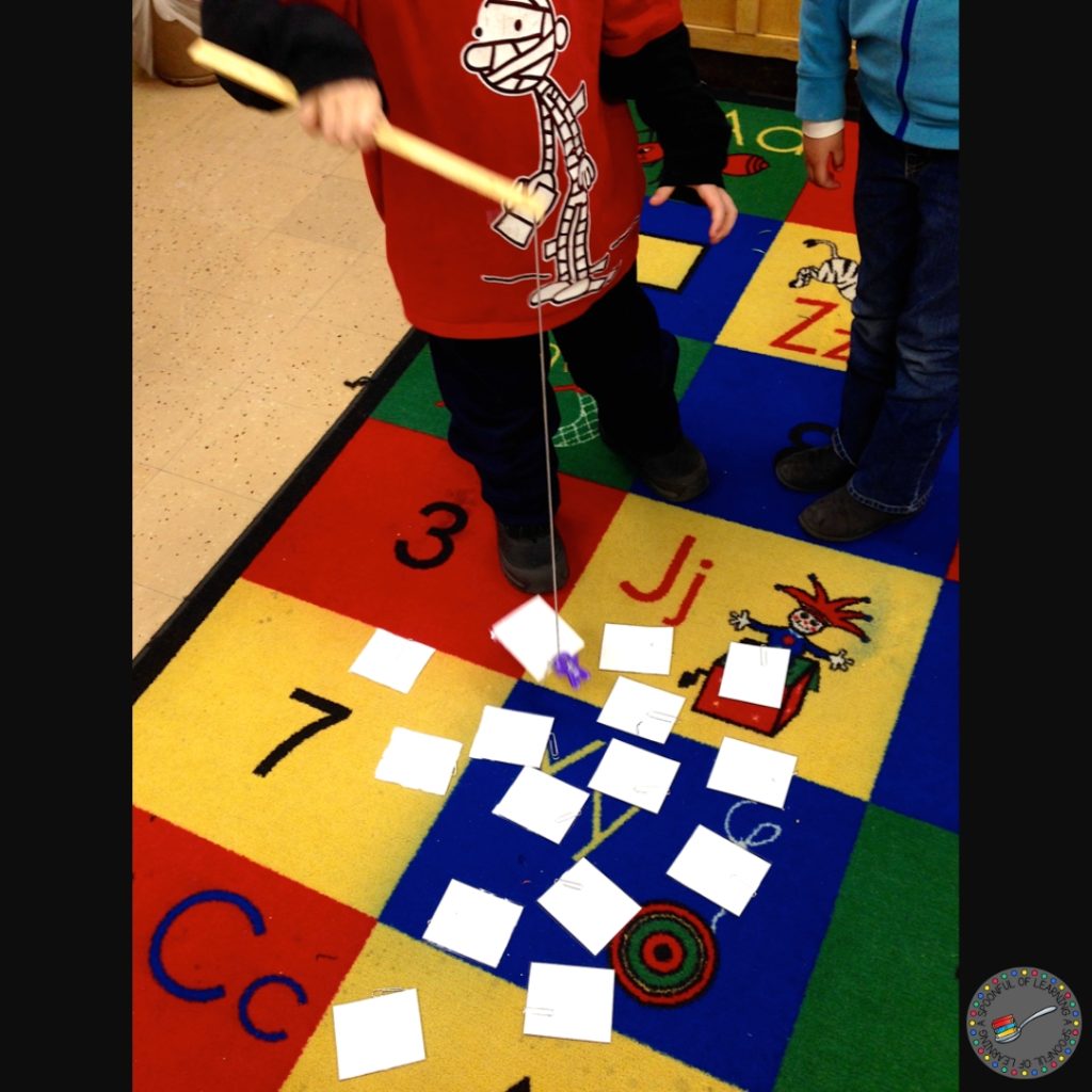 A child is fishing for cards on a colorful classroom carpet