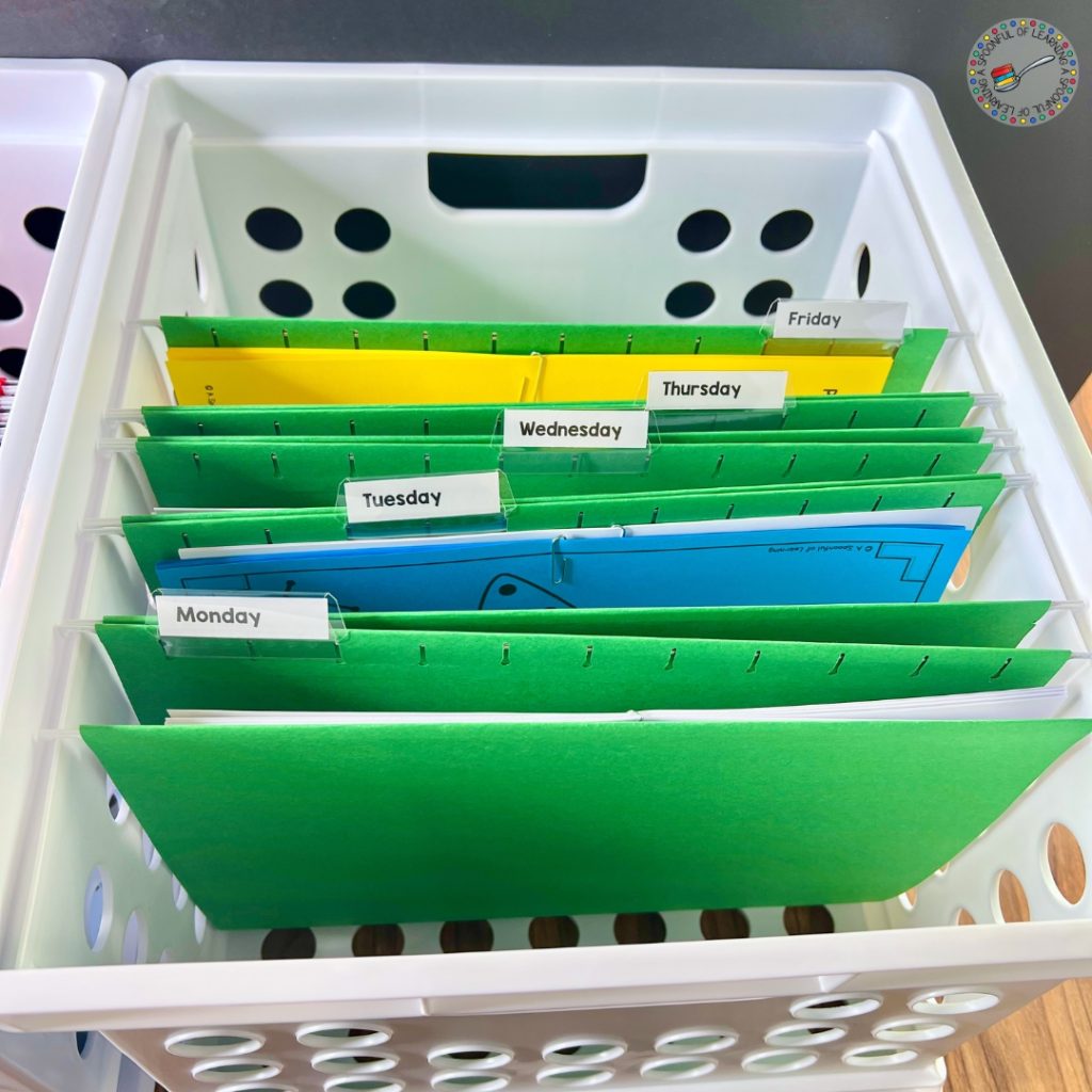 A white crate with green file folders containing lesson plan materials