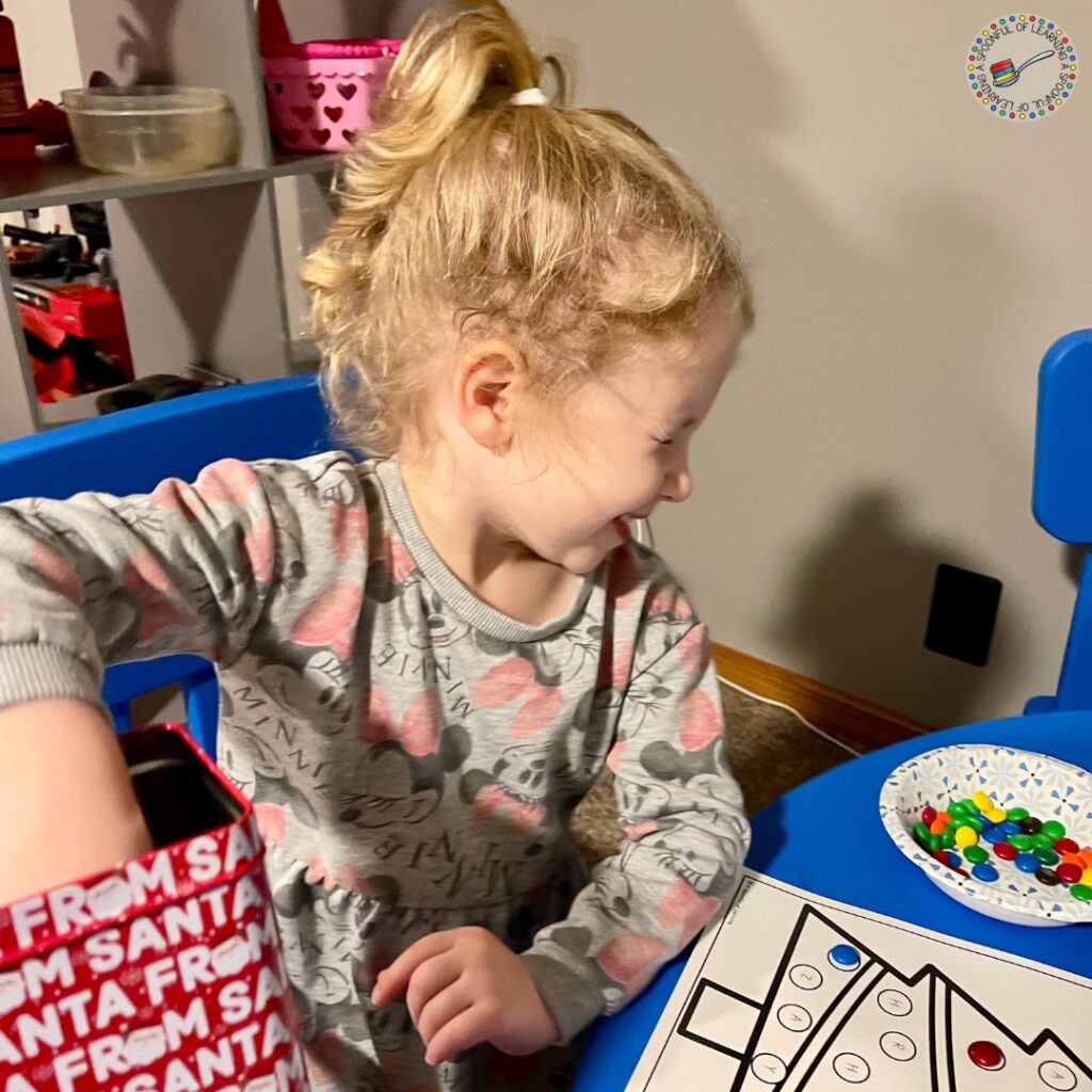 A smiling child closing her eyes and choosing a card from a tin