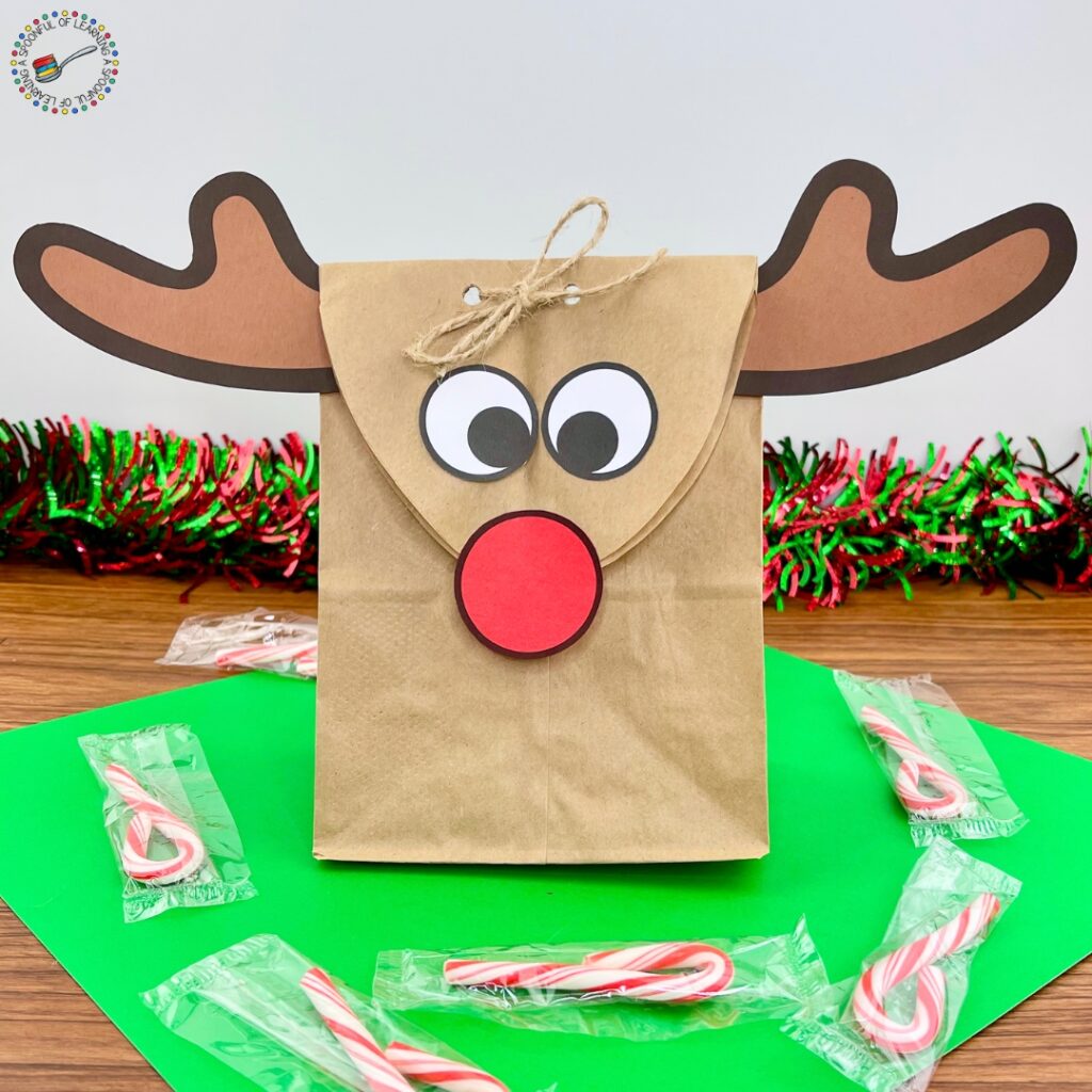 A completed paper bag reindeer craft with candy canes