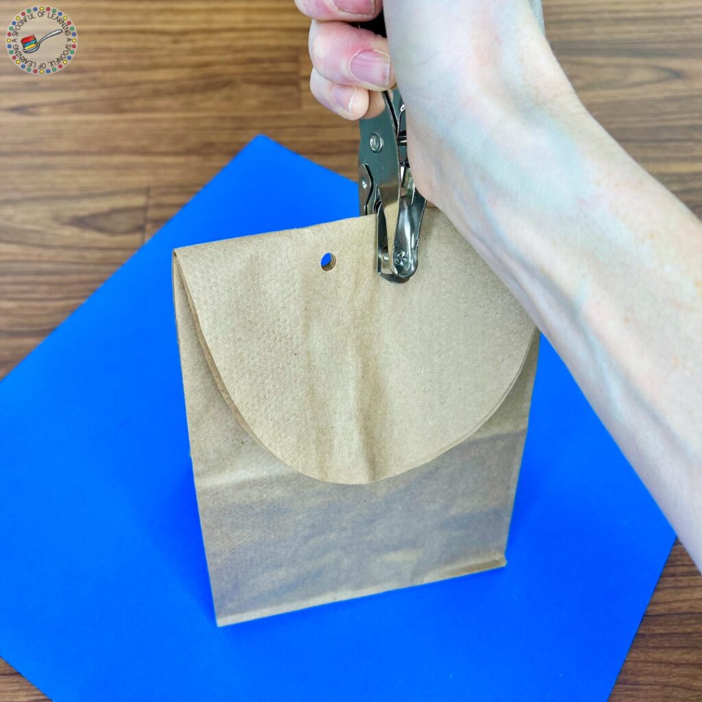 Using a hole punch to create two holes on the top of a folded bag